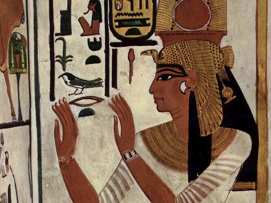 Egyptian tomb painting of Queen Nefertari with raised hands in adoration beside columns of hieroglyphs.