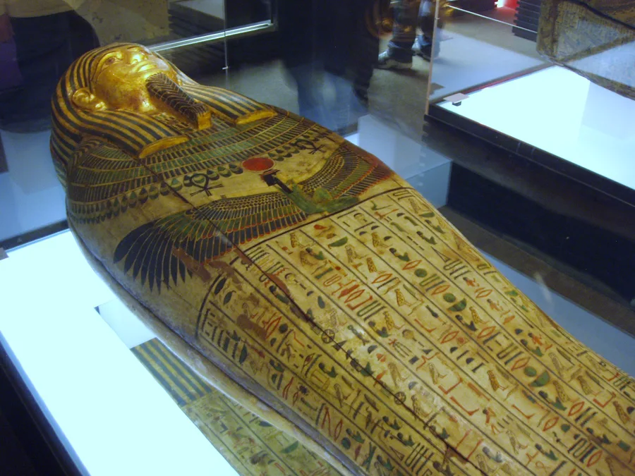 Polychrome Egyptian sarcophagus with dense hieroglyphic inscriptions and funerary imagery.