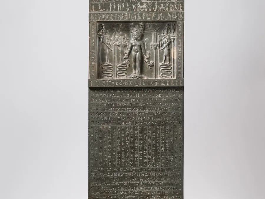 Egyptian magical stela showing Horus the Child with protective figures and hieroglyphs.